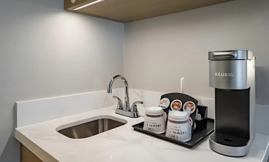 A modern kitchenette featuring a coffee maker and sink in a elegant hotel suite near Universal Studios Orlando.