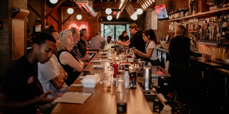 Adults seated at a bar with cocktails and food, participating in a craft cocktail class in downtown Orlando.
