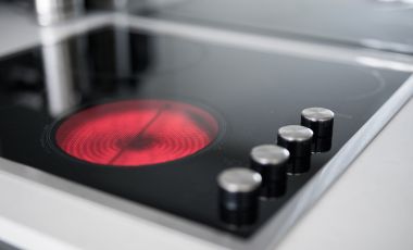 Close-up of a stove top featuring a red light, highlighting the kitchenette amenities at Long Stay Hotels Orlando.