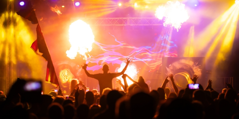 A lively crowd enjoying the Electric Daisy Carnival in Downtown Orlando, with flames and smoke creating an electrifying scene.