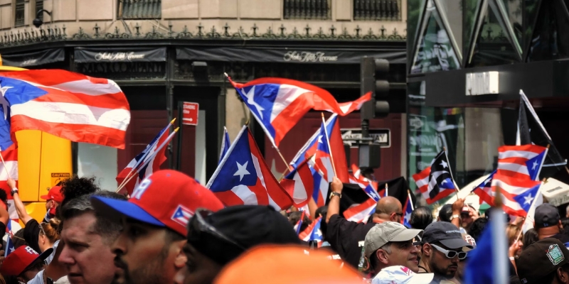 A lively street scene in downtown Orlando with a crowd holding Puerto Rican flags for the Florida Puerto Rican Parade & Festival.