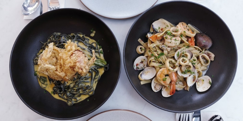 Two black plates artfully arranged with food, representing the dining experience at Downtown Orlando's Magical Dining event.
