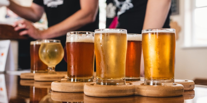 A wooden tray displays an assortment of beer glasses, perfect for a craft brewery and distillery tour during an Orlando bachelor party.