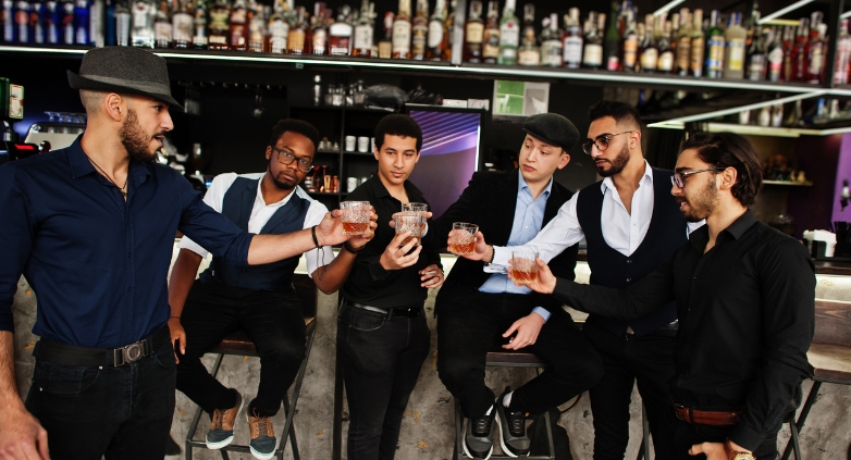 A group of men toasting drinks at a rooftop bar during an Orlando bachelor party celebration.