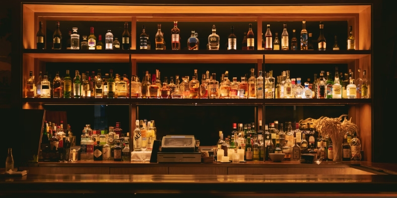 An inviting bar displaying a wide selection of alcohol bottles on shelves, perfect for a whiskey and BBQ celebration in Orlando.