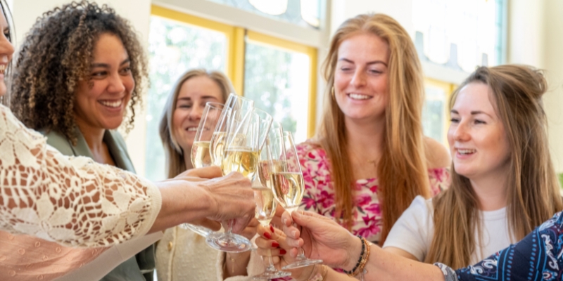 A lively group of women toasting with champagne glasses at an Orlando bachelorette party, enjoying a wine tasting celebration.