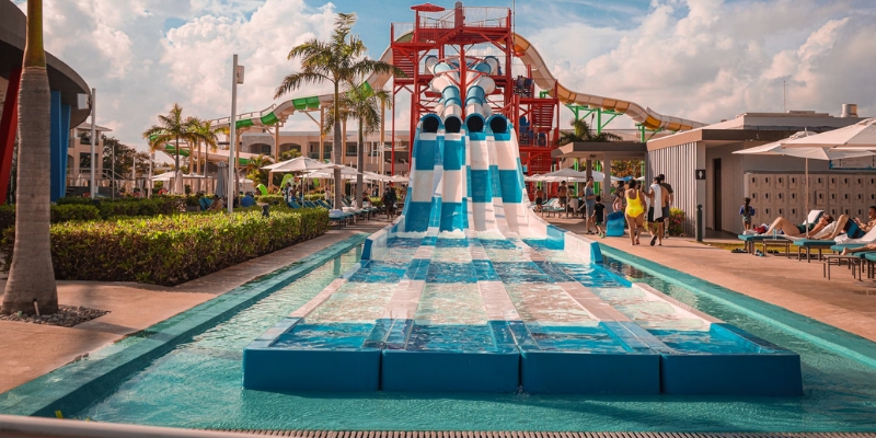 A vibrant water slide at a resort, leading into a large pool, showcasing fun activities in Downtown Orlando's nearby water park.