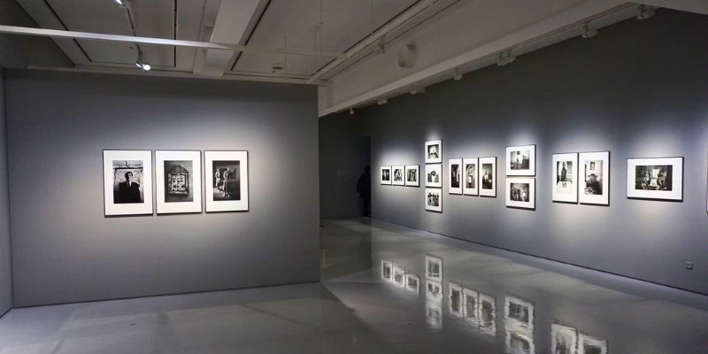 An art gallery featuring black walls adorned with white photographs, showcasing the Museum of Art in Orlando.