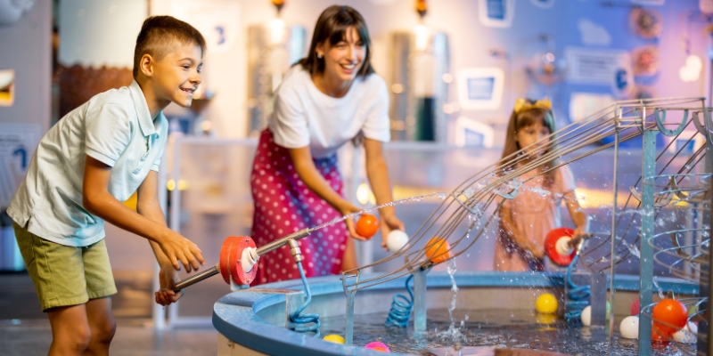 A family engages with water toys in the interactive exhibit at the Orlando Science Center, enjoying a summer day in August.