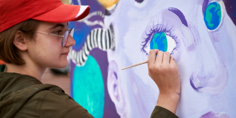 A young woman creates a colorful mural on a canvas during the Epcot International Festival of the Arts in February.