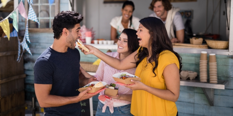 Three individuals savoring food at a food truck, showcasing Orlando's culinary offerings in January.