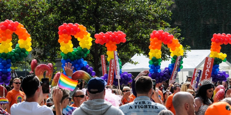People of various backgrounds gather, proudly holding rainbow balloons, marking the Pride festive atmosphere in Orlando this October.