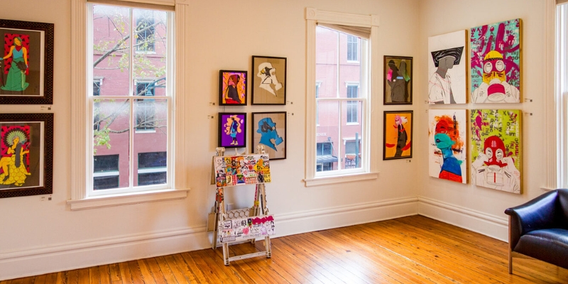 A room in the Downtown Arts District of Orlando, displaying multiple paintings on the walls.