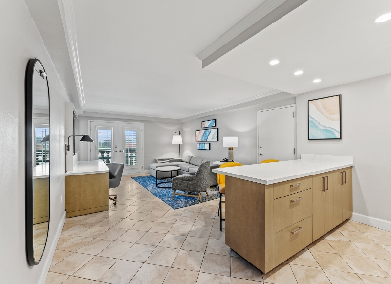 Spacious living room and kitchen area in a hotel near Winnie Palmer Hospital, Orlando, featuring a clean and modern design.