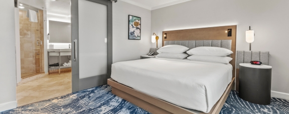 Hotel room showcasing a bed, bathroom, and shower, offering special rates for medical guests near Winnie Palmer Hospital, Orlando.