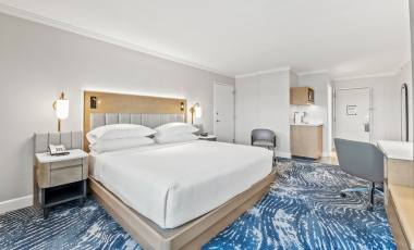 Comfortable hotel room with a bed, desk, and chair, ideal for rest and recovery near Winnie Palmer Hospital, Orlando.