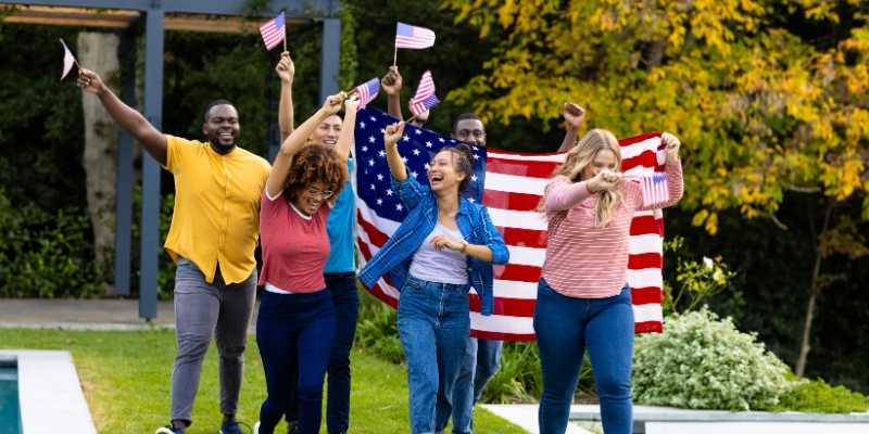 A group of people proudly holding American flags at an Orlando pool during a 4th of July Independence Day celebration.