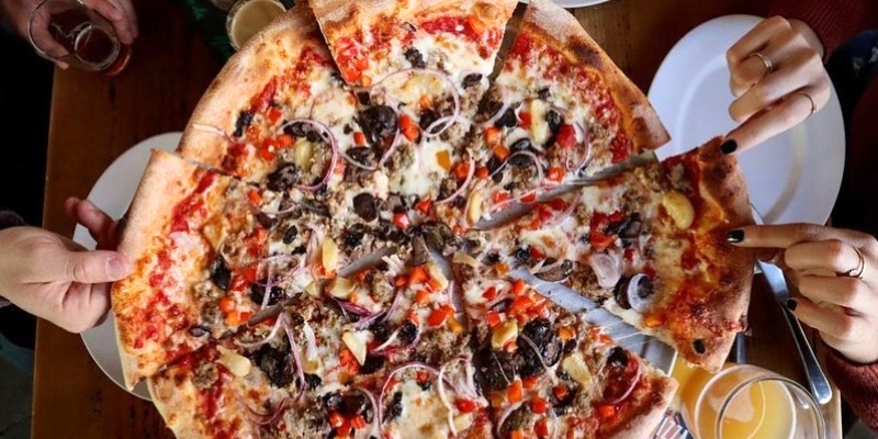 People gathered around a large pizza at Park Pizza & Brewing Company, celebrating the 4th of July in Orlando.