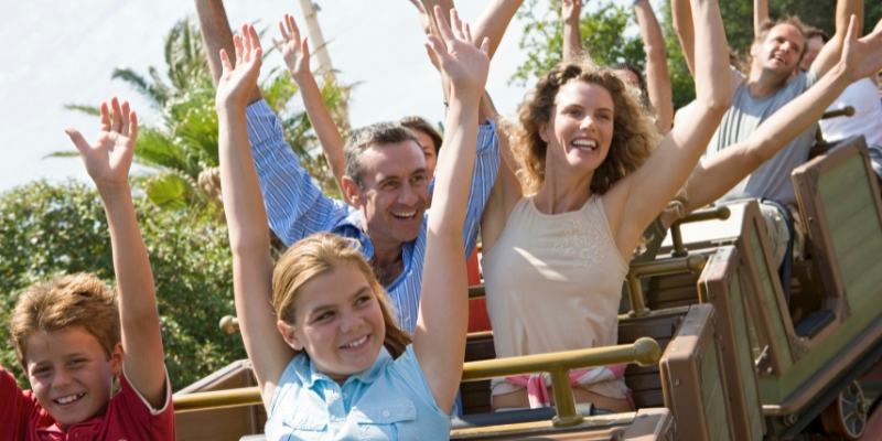 A family on a roller coaster, smiling and screaming with excitement during their fun-filled Orlando holiday.