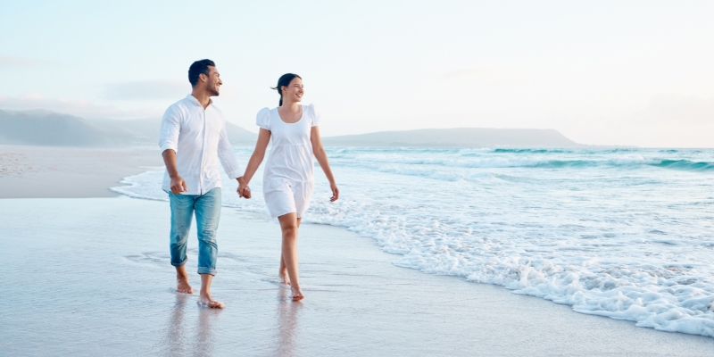 A couple walks hand in hand on the beach, sharing a romantic experience at Cocoa Beach, perfect for Orlando visitors.