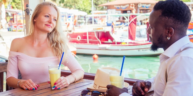 A couple sits at a table with drinks, enjoying a cozy atmosphere at The BOATHOUSE, a popular Orlando destination for couples.