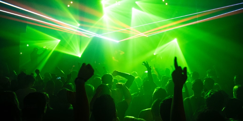 A bustling nightclub filled with people, featuring vibrant green lights, highlighting Orlando's nightlife and entertainment scene.