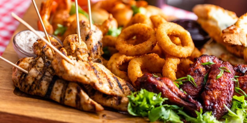 A wooden tray displaying chicken, onion rings, and various dishes, highlighting dining experiences in Downtown Orlando, Florida.