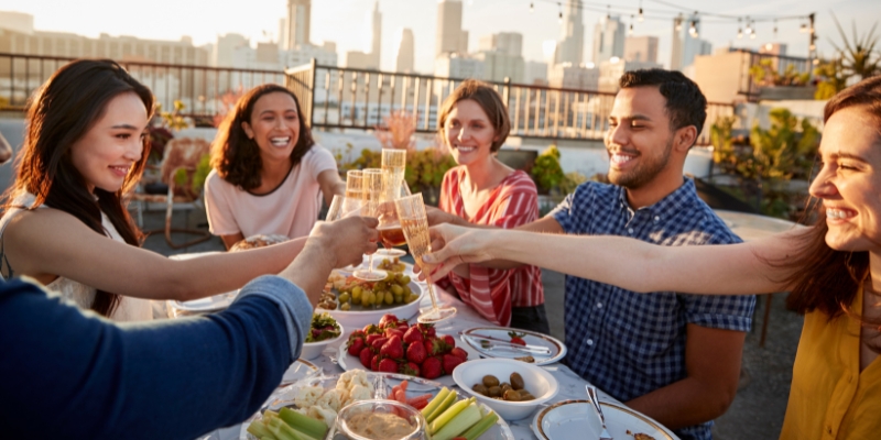 Friends celebrating with wine toasts at a dinner table during the Orlando 4th of July event at rooftop bars and lounges.