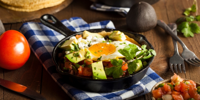 A vibrant skillet of Mexican cuisine with eggs, tomatoes, and avocado, from Hash House A Go Go near the Orlando Convention Center.