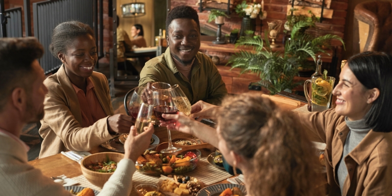 A group of people joyfully toasting drinks at a restaurant table in Pointe Orlando near the Convention Center.