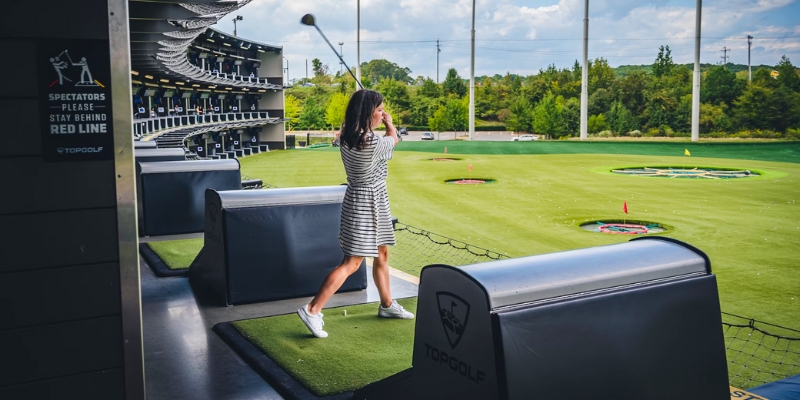 A woman plays golf on a scenic course, highlighting the attractions near the Orlando Convention Center, including Topgolf Orlando.
