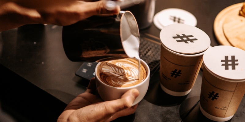 A barista pours hot coffee into a cup, surrounded by festive decorations in a downtown Orlando café during the holidays.
