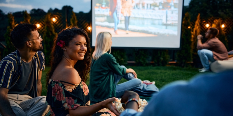 A group of people sitting on the grass at Lake Eola Park, enjoying a holiday movie during the Downtown Orlando Christmas event.