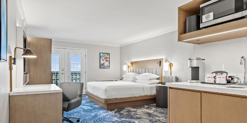 A cozy hotel room featuring a bed, desk, and microwave, ideal for a stay in downtown Orlando during Christmas.