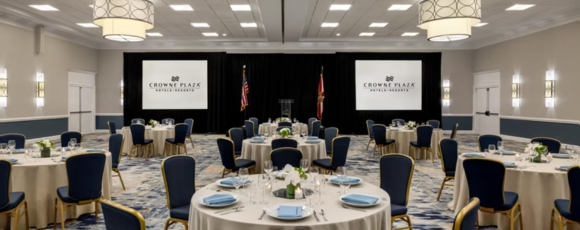 A professional banquet room with tables and chairs organized for a meeting, situated in a hotel near Amway Arena, Orlando.