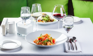 A dining table featuring two plates of food and wine glasses, highlighting nearby dining options in downtown Orlando.
