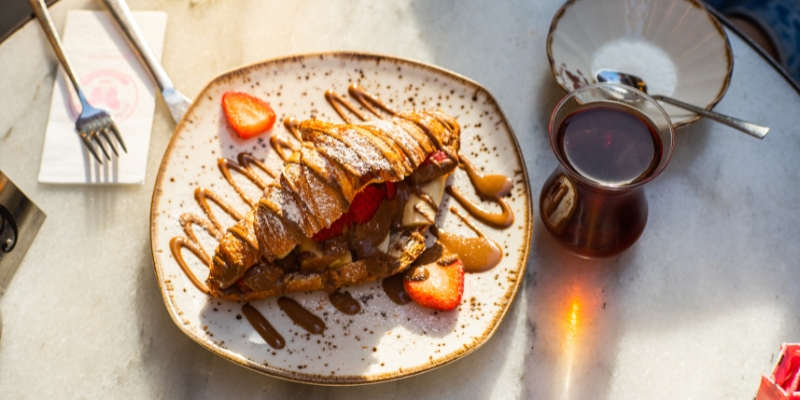 A croissant topped with chocolate sauce and fresh strawberries, elegantly presented on a plate at AC SkyBar in Orlando.