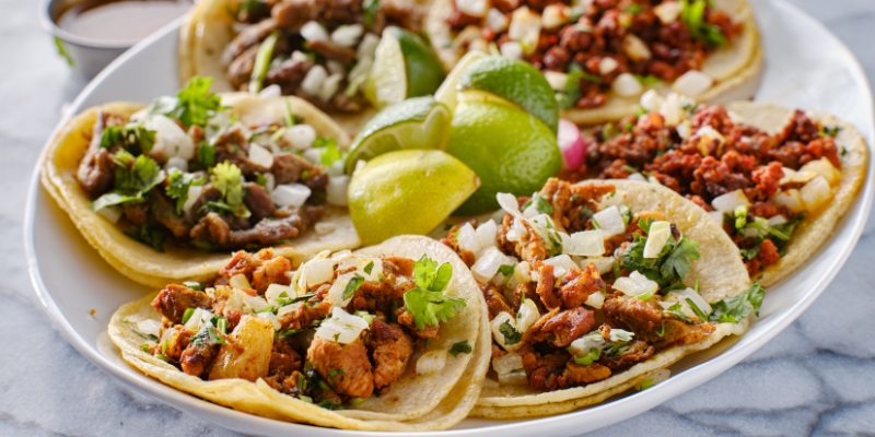 A plate of tacos filled with meat, topped with onions and served with lime, featured at Café Tu Tu Tango in Orlando.