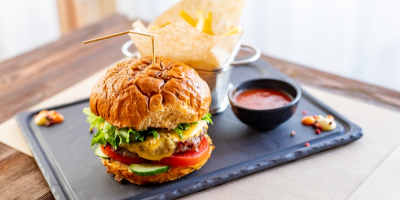 A delicious hamburger accompanied by fries and ketchup on a tray, representing unique dining experiences at Orlando's City Food Hall.