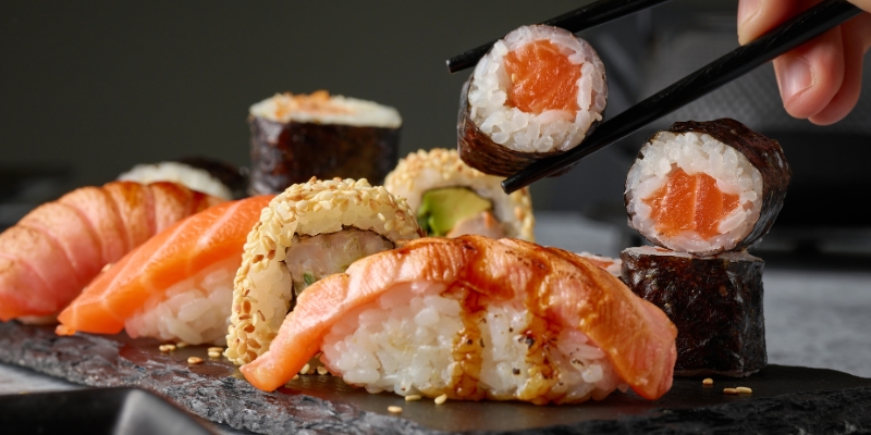 A diner with chopsticks poised over sushi at Kabooki Sushi, representing a unique culinary experience in Orlando.