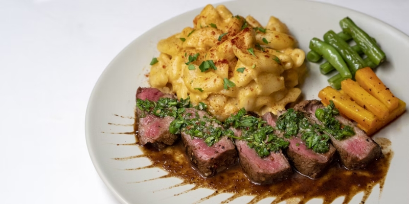 A plate featuring a juicy steak, creamy macaroni and cheese, and vibrant green beans at STK, Disney Springs, Orlando.