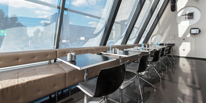 Dining area with tables and chairs in front of a large window, highlighting The Balcony Orlando's unique atmosphere.