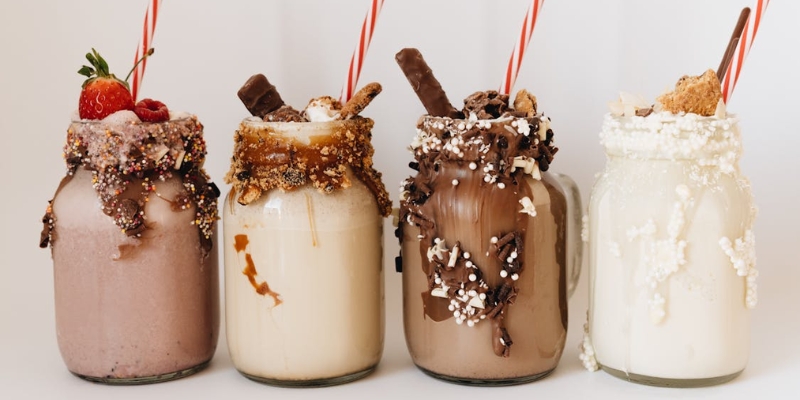 Four colorful milkshakes topped with whipped cream, sprinkles, and chocolate, featured at Toothsome Chocolate Emporium in Orlando.
