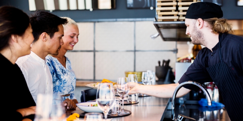 Chef serving gourmet dishes to customers in a vibrant Orlando restaurant, showcasing unique dining experiences.